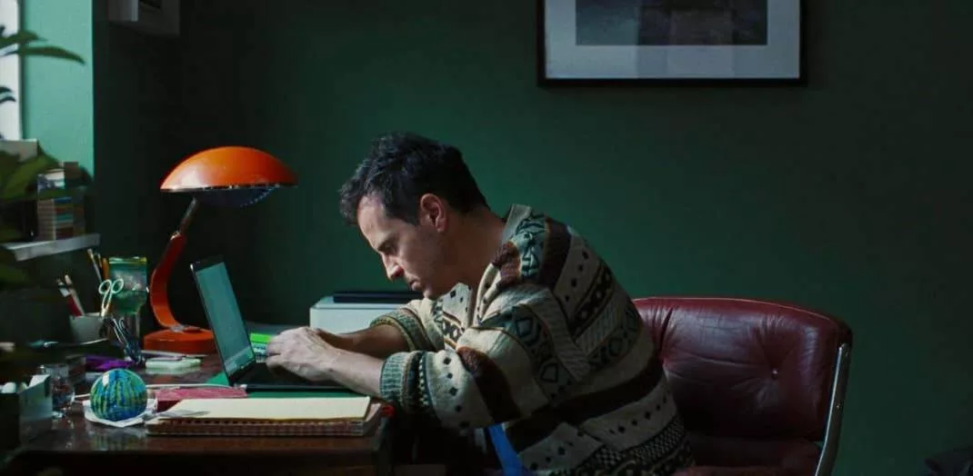 andrew scottt protagonista de todos somos extraños recargado en su escritorio